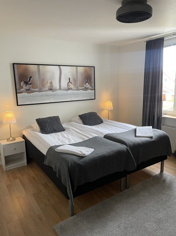 Ljust rum med två sängar, trägolv och fågelbild, ej konferensrum